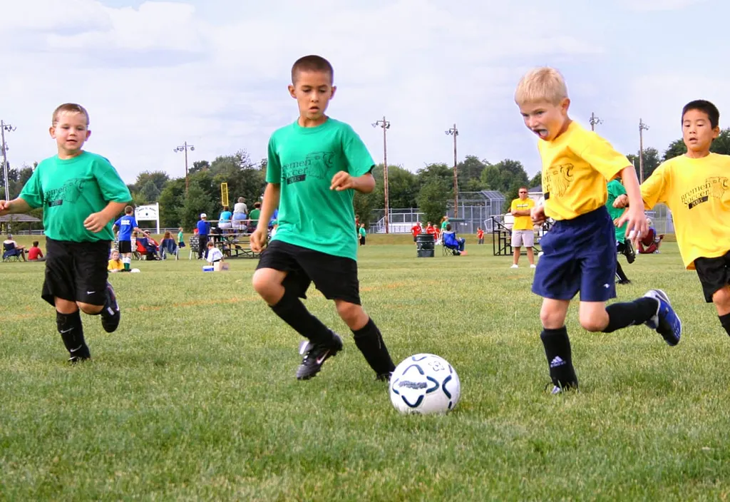 Kinder beim Fußballspiel auf dem Rasen, ein Junge führt den Ball
